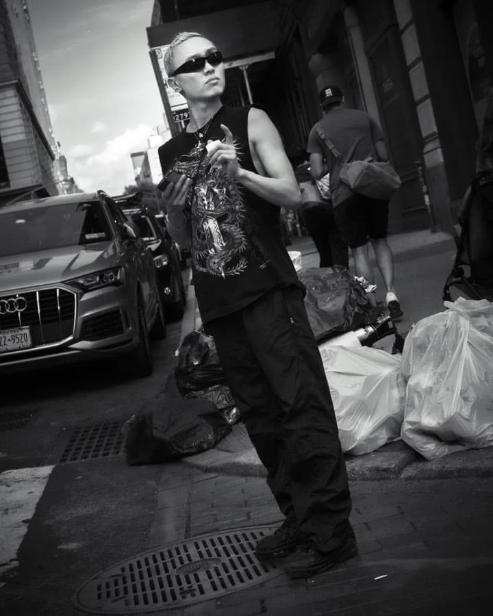 Black-and-white street portrait of a man in sunglasses on a city sidewalk
