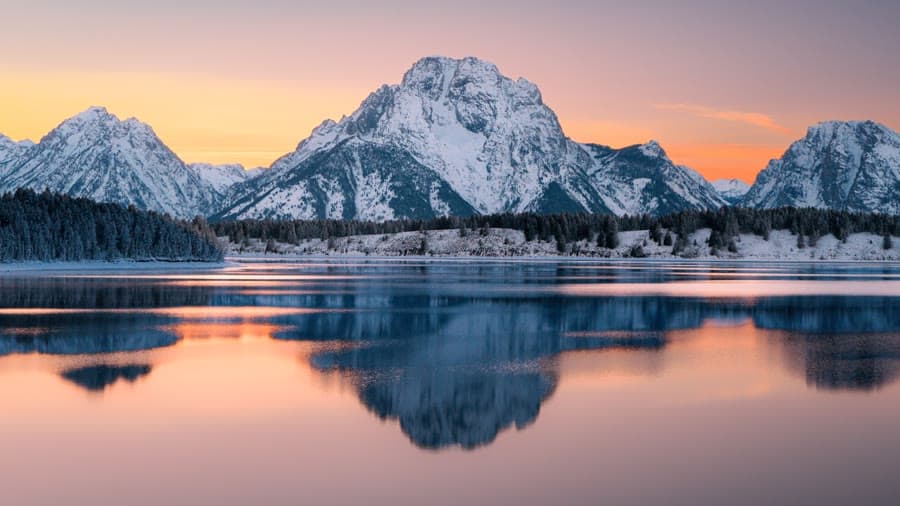Snow-capped peak reflected in a still lake at sunrise