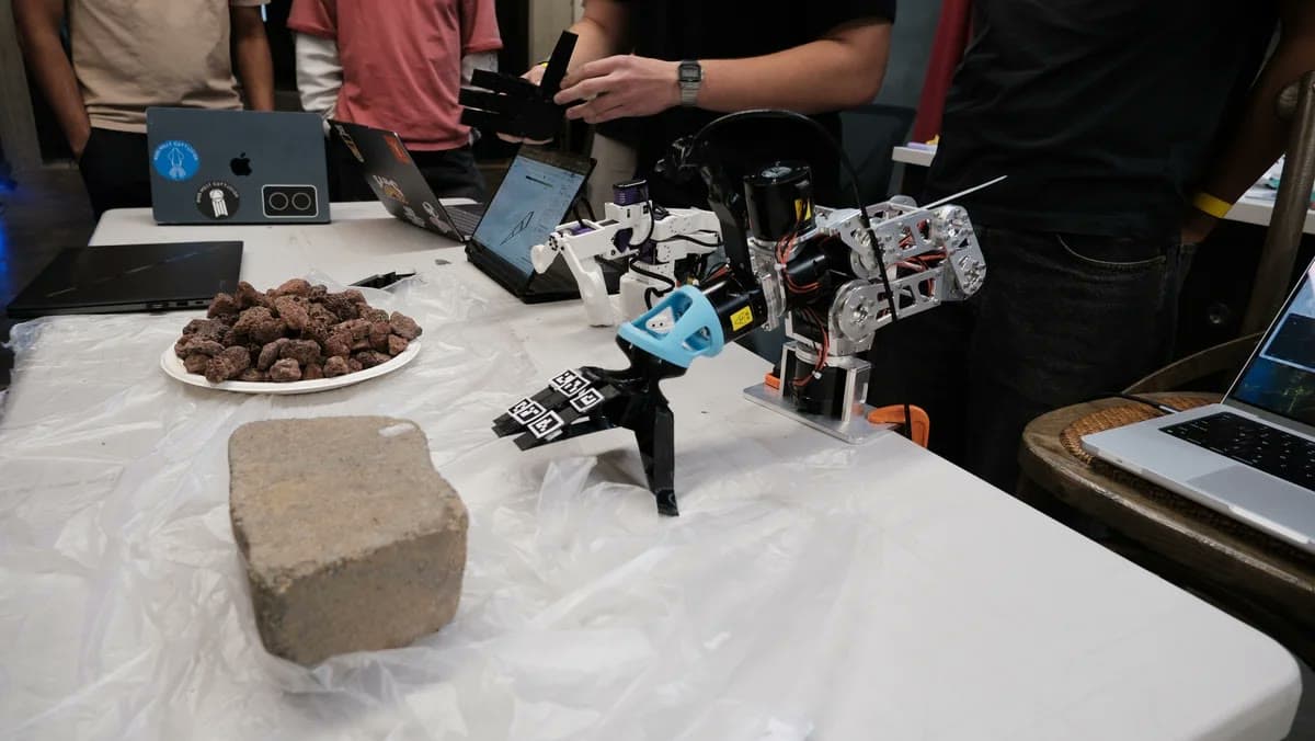 Scrambler robotic hand on a demo table beside a brick