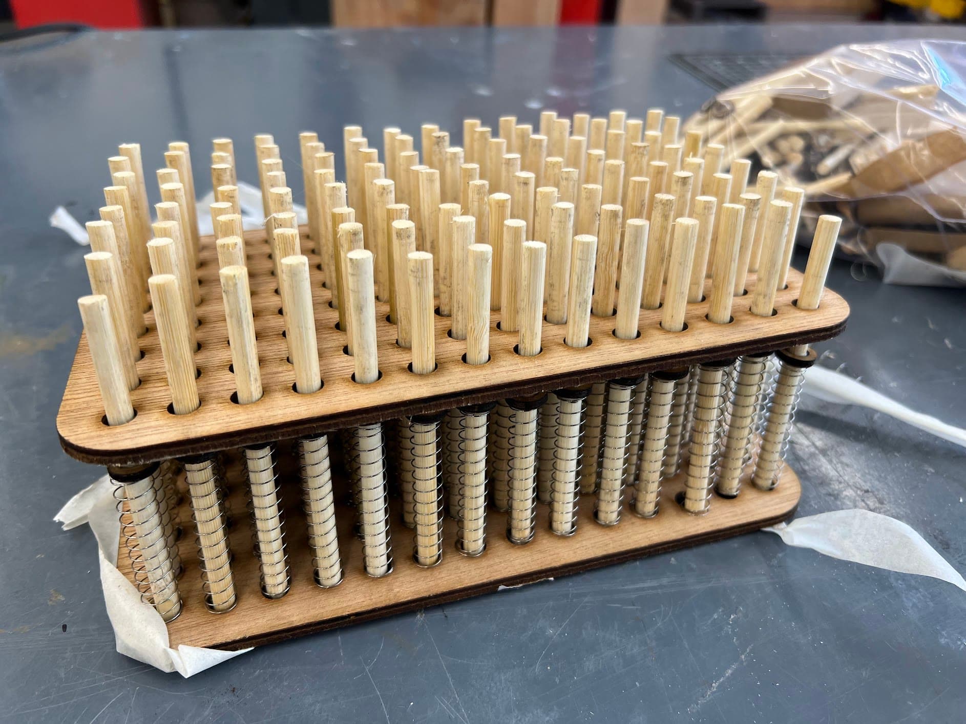 Laser-cut wooden frame holding the spring-loaded pins